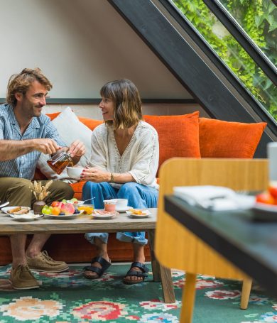 Un couple qui prend son petit déjeuner en face à face sur le canapé de l'hôtel.