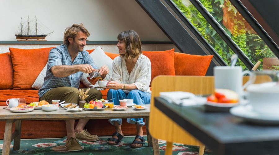 Un couple qui prend son petit déjeuner en face à face sur le canapé de l'hôtel.